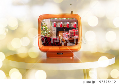 Tv showing movie of Armchair with plaid, packing gift boxes for family and glass of wine near christmas tree and fireplace. Top view . Tv showing movie of Armchair with plaid, packing gift boxes for family and glass of wine near christmas tree and fireplace. Top view . 97576412