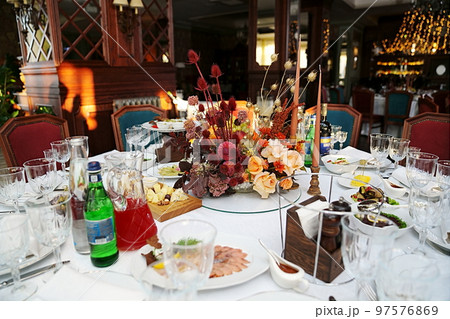 table setting for a festive dinner. flowers, wine glasses, tableware and snacks. 97576869