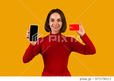 Smiling young woman holding smartphone and credit card, mockup 97579021