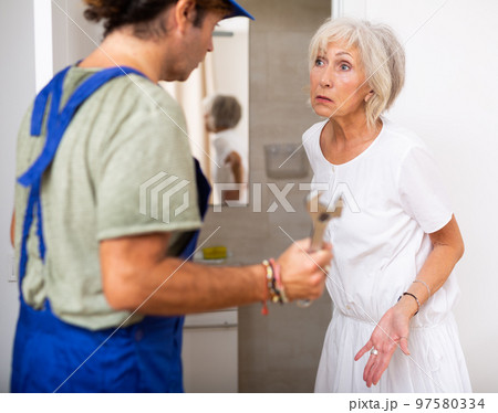 Elderly woman talking with plumber at home 97580334