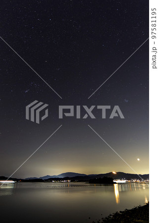 瀬戸内のかがり火灯る山に沈む三日月とオリオン座 97581195
