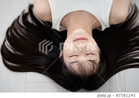 フローリングに寝転ぶタンクトップの若い女性 97581245