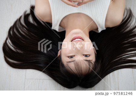 フローリングに寝転ぶタンクトップの若い女性 97581246