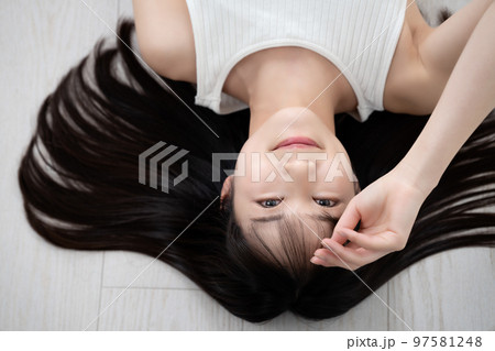 フローリングに寝転ぶタンクトップの若い女性 フローリングに寝転ぶタンクトップの若い女性 97581248