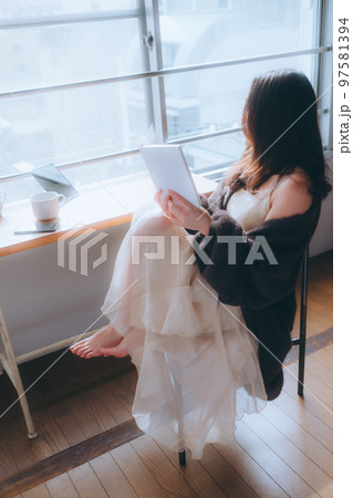 部屋で読書をする若い女性の写真 97581394
