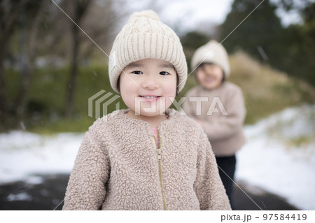 冬に雪遊びしているニット帽をかぶった女の子の姉妹 冬に雪遊びしているニット帽をかぶった女の子の姉妹 97584419