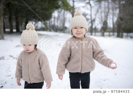 冬に雪遊びしているニット帽をかぶった女の子の姉妹 冬に雪遊びしているニット帽をかぶった女の子の姉妹 97584435