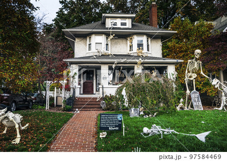 Many colorful Halloween decorations, skeletons, scarecrows at driveway and front lawn of house. Many colorful Halloween decorations, skeletons, scarecrows at driveway and front lawn of house. 97584469
