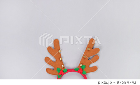 Deer antlers headband hiding on grey background. Concept of winter holidays, new year, Christmas. Christmas composition. Top view. Copy space. 97584742