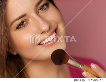 Beautiful young woman applying cosmetic powder product with make-up bamboo brush, beauty, makeup and skincare cosmetics model face portrait on pink background, closeup 97588043