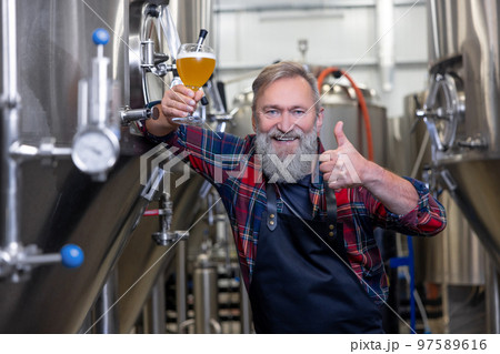 Brewery owner demostrating his product and looking proud 97589616