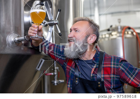 Brewery owenr tasting fresh beer and looking interested 97589618