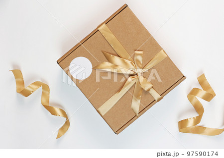 The gift box is made of craft cardboard. The box is tied with a beige satin ribbon.Flat lay.View from above.Space for copying.Packaging for gifts. A surprise for the holiday. The gift box is made of craft cardboard. The box is tied with a beige satin ribbon.Flat lay.View from above.Space for copying.Packaging for gifts. A surprise for the holiday. 97590174