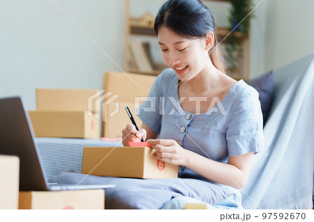 Starting small business entrepreneur of independent young Asian woman online seller is using computer and taking orders to pack products for delivery to customers. SME delivery concept. 97592670