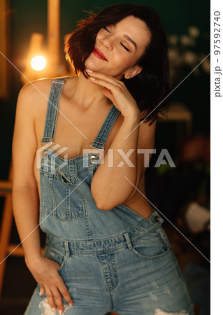 an attractive brunette with a denim jumpsuit on her naked body.  97592740
