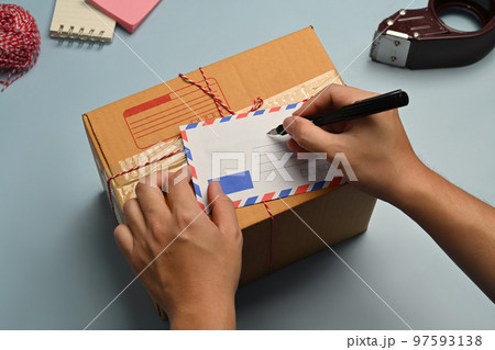 Above view of man signing greeting card, surrounded by gift wrapping materials on blue background Above view of man signing greeting card, surrounded by gift wrapping materials on blue background 97593138