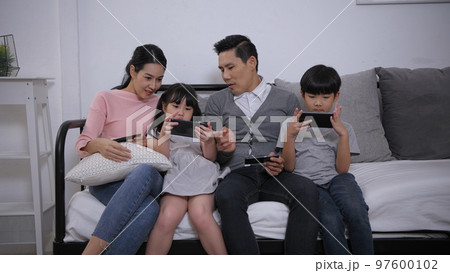 Family concept of 4k Resolution. Asian parents and children playing with mobile phones in the living room 97600102