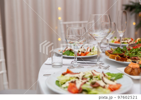 Served for holiday banquet restaurant table with dishes, snack, cutlery, wine and water glasses. 97602521