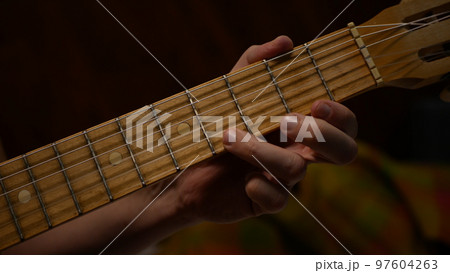 Playing the guitar. Strumming acoustic guitar. Man s hand with a guitar neck Playing the guitar. Strumming acoustic guitar. Man s hand with a guitar neck 97604263