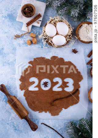 Gingerbread dough for cookies in shape of 2023 97607506
