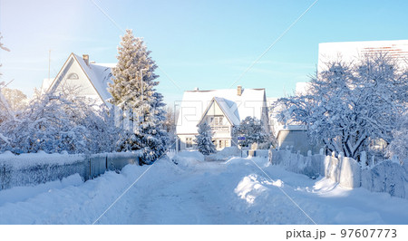Winter fairy-tale landscape on the street with houses with a triangular roof and roads covered with a lot of snow 97607773