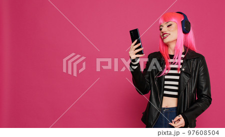 Hipster trendy female model using videocall conference on smartphone, talking to people on online videoconference. Cool stylish girl chatting on remote teleconference call in studio. Hipster trendy female model using videocall conference on smartphone, talking to people on online videoconference. Cool stylish girl chatting on remote teleconference call in studio. 97608504