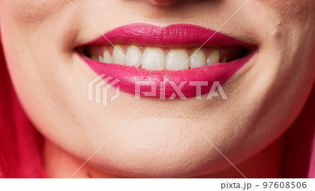 Cheerful female model showing candid smile in studio, wearing glamour pink lipstick and smiling. Beautiful attractive person acting flirty expressing passion. Macro shot, extreme closeup. Cheerful female model showing candid smile in studio, wearing glamour pink lipstick and smiling. Beautiful attractive person acting flirty expressing passion. Macro shot, extreme closeup. 97608506
