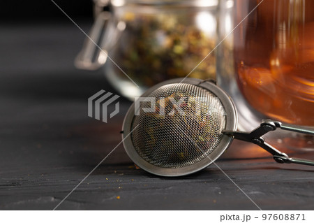 Metal tea strainer on black wooden table 97608871