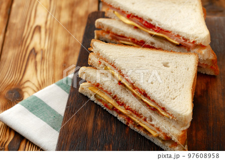 Sandwiches cut into halves on wooden cutting board with napkin Sandwiches cut into halves on wooden cutting board with napkin 97608958
