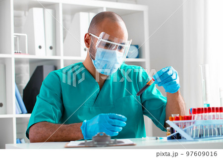 African american doctor or laboratory worker examines blood sample in clinic 97609016