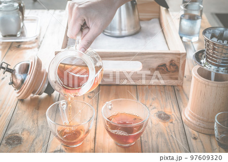 Barista pouring a hot coffee after dip coffee in a glass cup of coffee. 97609320