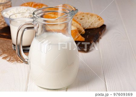 Glass jar of milk, bowl of cottage cheese and bread on wooden table 97609369