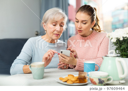Young woman teaching her senior mother to use smartphone Young woman teaching her senior mother to use smartphone 97609464