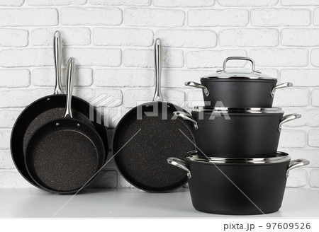 Set of cookware on table against white brick wall Set of cookware on table against white brick wall 97609526