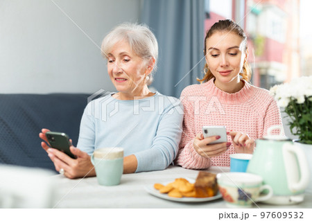 Senior woman and her granddaughter using smartphones at home 97609532