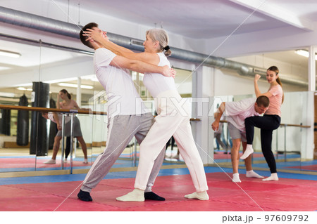 Sportive woman conducts painful reception on the eyes of man in gym. Self defense lessons 97609792