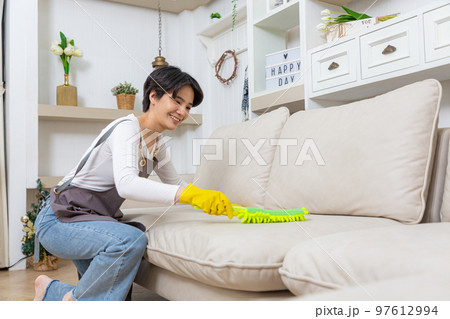 Hygiene and cleanliness in the living room. A Cleaning lady with gloves wipes dust from furniture with a cloth. Hygiene and cleanliness in the living room. A Cleaning lady with gloves wipes dust from furniture with a cloth. 97612994