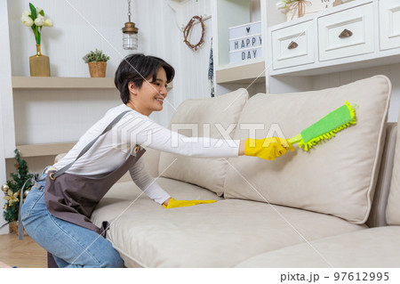 Hygiene and cleanliness in the living room. A Cleaning lady with gloves wipes dust from furniture with a cloth. Hygiene and cleanliness in the living room. A Cleaning lady with gloves wipes dust from furniture with a cloth. 97612995