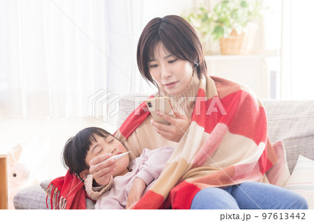 発熱した子供を抱っこしてスマホで病院を検索するママ 発熱した子供を抱っこしてスマホで病院を検索するママ 97613442