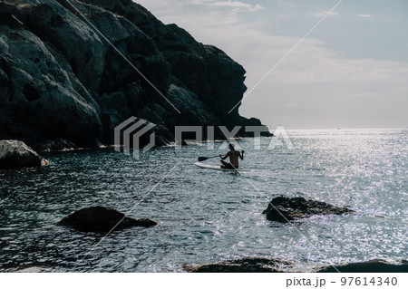 Side view foto of a man swiming and relaxing on the sup board. Sportive man in the sea on the Stand Up Paddle Board SUP. The concept of an active and healthy life in harmony with nature. Side view foto of a man swiming and relaxing on the sup board. Sportive man in the sea on the Stand Up Paddle Board SUP. The concept of an active and healthy life in harmony with nature. 97614340