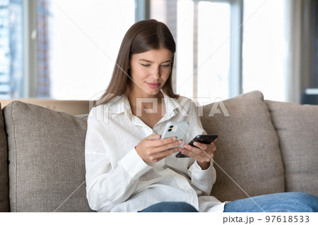 Engaged digital addict girl using two smartphones for data Engaged digital addict girl using two smartphones for data 97618533