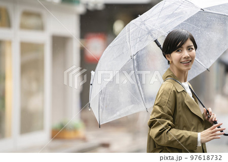ビニール傘をさした笑顔の30代前半の女性　雨の日 97618732