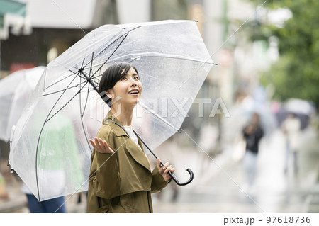 ビニール傘をさして空を見上げる若い女性 97618736