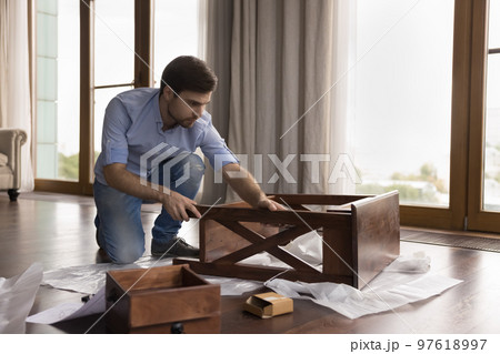 Focused serious homeowner man assembling new piece of furniture 97618997