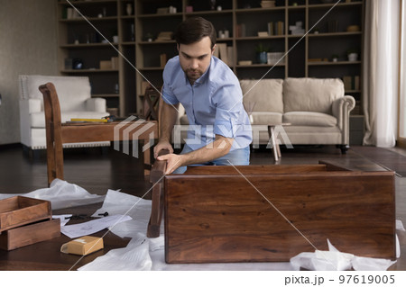 Serious busy homeowner man assembling piece of furniture Serious busy homeowner man assembling piece of furniture 97619005