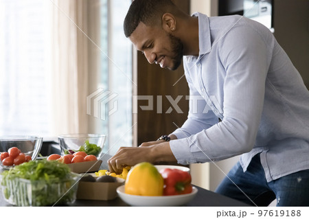 Happy handsome young African chef guy cooking vegan meal Happy handsome young African chef guy cooking vegan meal 97619188