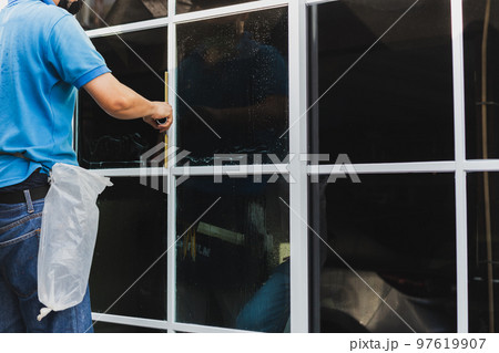 Worker use scraper cleaning window before installing tinting film. Worker use scraper cleaning window before installing tinting film. 97619907