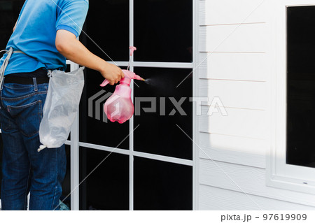 Unidentified man wrapper tinting a window with tinted foil using foggy spray. 97619909