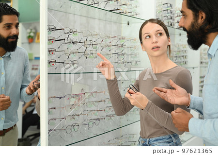 Young caucasian woman choosing a new eyeglasses frame with optician. Eyesight, vision and health care concept Young caucasian woman choosing a new eyeglasses frame with optician. Eyesight, vision and health care concept 97621365