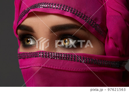 Close-up shot of a young charming woman wearing the pink hijab decorated with sequins. Arabic style. Close-up shot of a young charming woman wearing the pink hijab decorated with sequins. Arabic style. 97621563